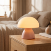 Mushroom LED touch lamp in soft blush pink on a wooden nightstand